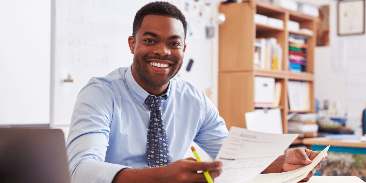 Teacher smiling in classroom with papers